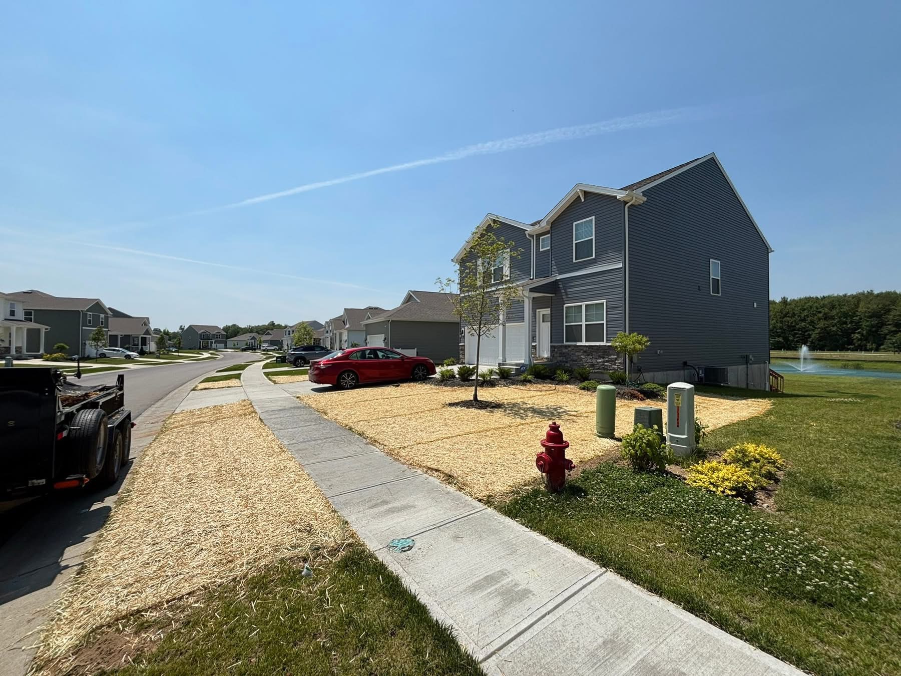 New construction home with fresh lawn seeding and straw covering — new yard installation