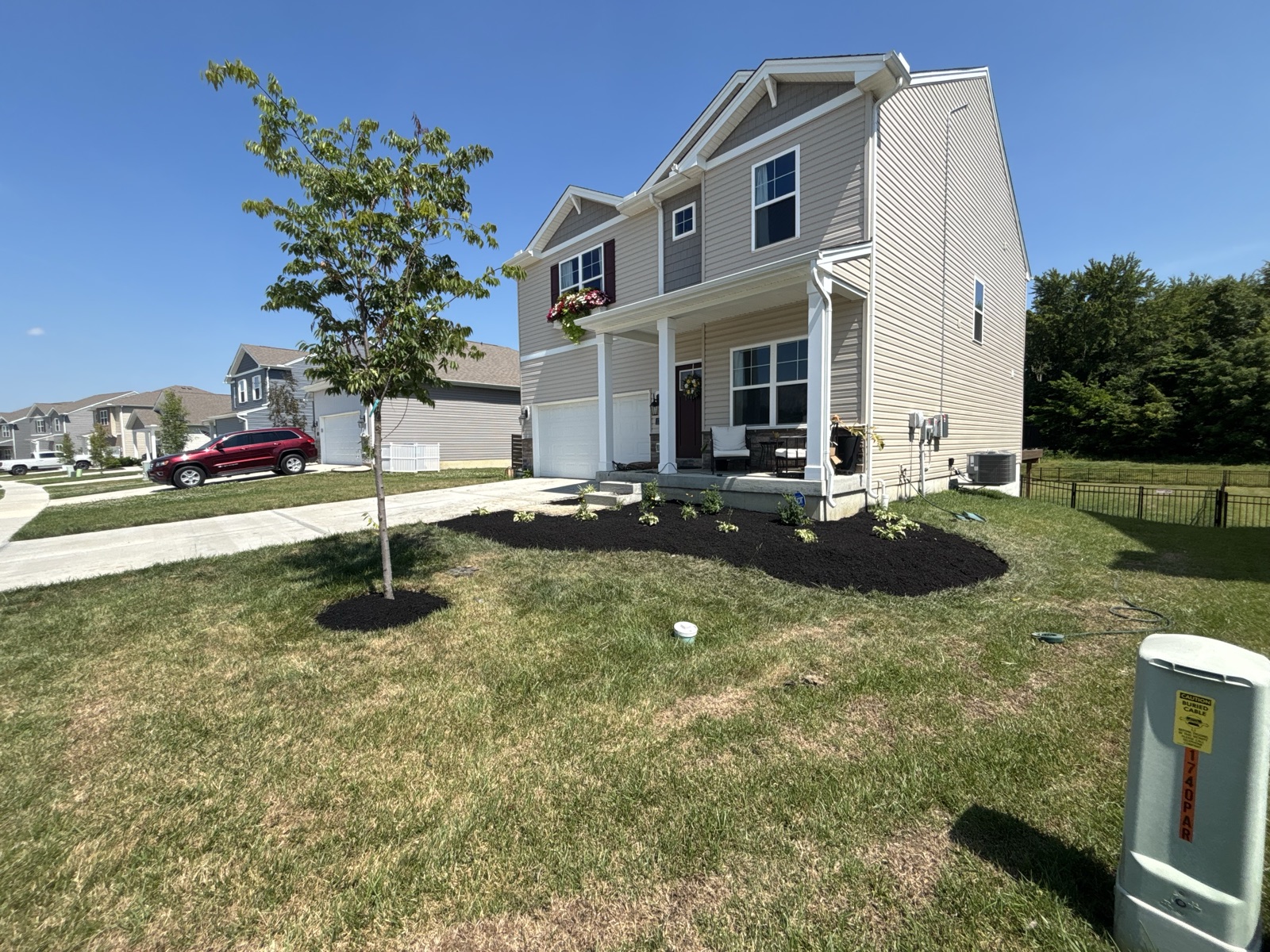 New landscape installation with dark mulch beds, fresh tree planting, and stone accents